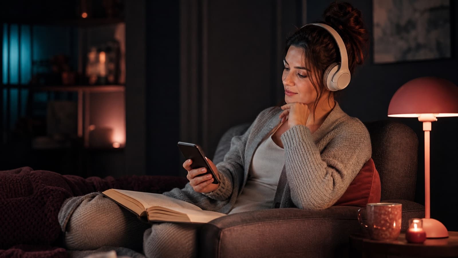 Adult woman choosing between a romance novel and audio listening on her phone in a quiet evening reading corner